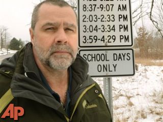 Greg Smith stands next to the multiple school speed limit sign on Boogie Lake Road, south of Highland Road in White Lake, Mich. on Feb. 14, 2012. (AP Photo, The Oakland Press, Tim Thompson)