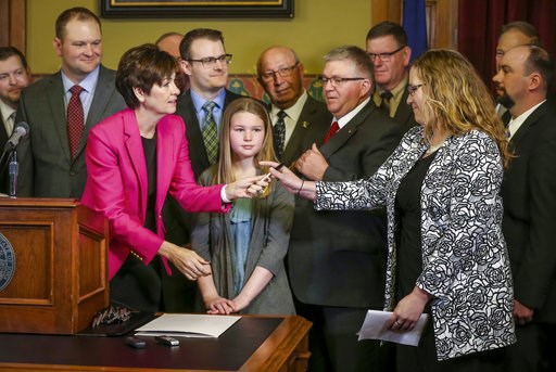 (Rodney White/The Des Moines Register via AP). In this April 2, 2018 photo, Gov. Kim Reynolds hands out pens to attendees after signing a bill allowing unregulated health plans at the Iowa Statehouse in Des Moines, Iowa. The Iowa law approved this spri... (Rodney White/The Des Moines Register via AP). In this April 2, 2018 photo, Gov. Kim Reynolds hands out pens to attendees after signing a bill allowing unregulated health plans at the Iowa Statehouse in Des Moines, Iowa. The Iowa law approved this spri...
