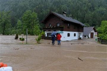 (AP Photo/Kerstin Joensson). Two residents stand on a flooded street near the Saalach river in Weissbach in the Austrian province of Salzburg, Sunday, June. 2, 2013.