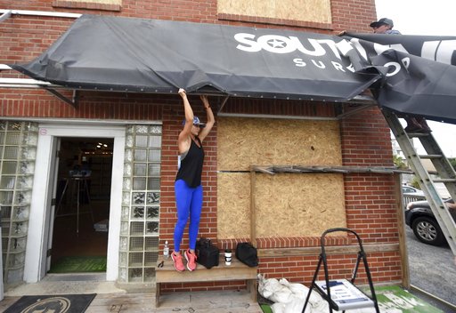 (Matt Born/The Star-News via AP, File). FILE- In this Sept. 11, 2018, file photo Ashley DeGroote, left, and husband Jeff DeGroote remove the awning at South End Surf Shop in Wrightsville Beach, N.C., in preparation for Hurricane Florence. Though it’s f... (Matt Born/The Star-News via AP, File). FILE- In this Sept. 11, 2018, file photo Ashley DeGroote, left, and husband Jeff DeGroote remove the awning at South End Surf Shop in Wrightsville Beach, N.C., in preparation for Hurricane Florence. Though it’s f...