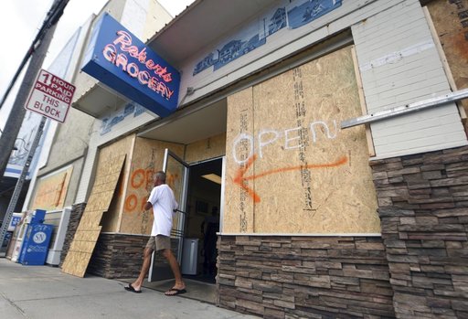 (Matt Born/The Star-News via AP, File). FILE- In this Tuesday, Sept. 11, 2018, file photo a man walks out of the boarded up Robert's Grocery in Wrightsville Beach, N.C., in preparation for Hurricane Florence. Though it’s far from clear how much economi... (Matt Born/The Star-News via AP, File). FILE- In this Tuesday, Sept. 11, 2018, file photo a man walks out of the boarded up Robert's Grocery in Wrightsville Beach, N.C., in preparation for Hurricane Florence. Though it’s far from clear how much economi...