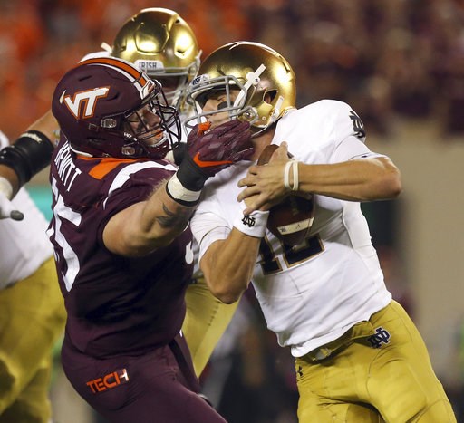 (Matt Gentry/The Roanoke Times via AP). Virginia Tech's Jarrod Hewitt (55) grabs Notre Dame quarterback Ian Book (12) by the face mask and is called for a personal foul during the first quarter of an NCAA college football game Saturday, Oct. 6, 2018, i... (Matt Gentry/The Roanoke Times via AP). Virginia Tech's Jarrod Hewitt (55) grabs Notre Dame quarterback Ian Book (12) by the face mask and is called for a personal foul during the first quarter of an NCAA college football game Saturday, Oct. 6, 2018, i...