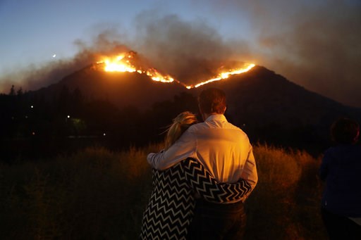 (AP Photo/Marcio Jose Sanchez). Roger Bloxberg, right, and his wife Anne hug as they watch a wildfire on a hill top near their home Friday, Nov. 9, 2018, in West Hills, Calif. (AP Photo/Marcio Jose Sanchez). Roger Bloxberg, right, and his wife Anne hug as they watch a wildfire on a hill top near their home Friday, Nov. 9, 2018, in West Hills, Calif.