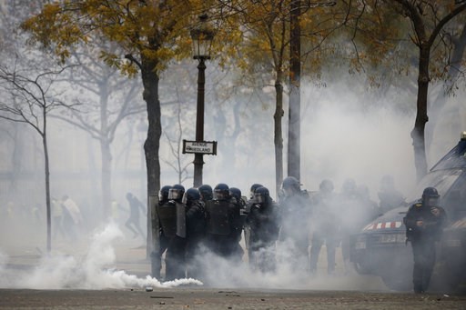 (AP Photo/Kamil Zihnioglu). French riot police officers take position amid tear gas during a demonstration Saturday, Dec. 1, 2018 in Paris. French authorities have deployed thousands of police on Paris' Champs-Elysees avenue to try to contain protests ... (AP Photo/Kamil Zihnioglu). French riot police officers take position amid tear gas during a demonstration Saturday, Dec. 1, 2018 in Paris. French authorities have deployed thousands of police on Paris' Champs-Elysees avenue to try to contain protests ...