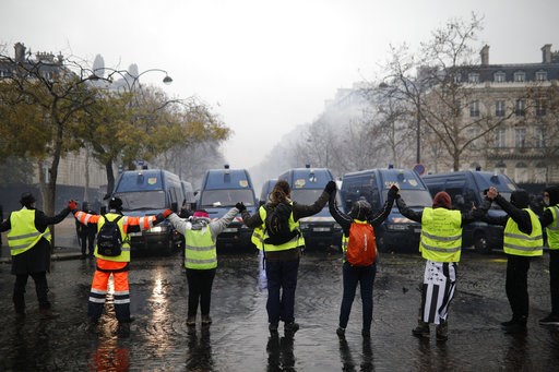 (AP Photo/Kamil Zihnioglu). Demonstrators wearing yellow jackets make a chain in front of police forces near the Champs-Elysees avenue during a demonstration Saturday, Dec.1, 2018 in Paris. French authorities have deployed thousands of police on Paris'... (AP Photo/Kamil Zihnioglu). Demonstrators wearing yellow jackets make a chain in front of police forces near the Champs-Elysees avenue during a demonstration Saturday, Dec.1, 2018 in Paris. French authorities have deployed thousands of police on Paris'...