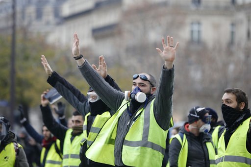 (AP Photo/Kamil Zihnioglu). Masked demonstrators wearing yellow jackets raise their hands near the Champs-Elysees avenue during a demonstration Saturday, Dec.1, 2018 in Paris. Scuffles broke out between some French protesters angry over rising taxes an... (AP Photo/Kamil Zihnioglu). Masked demonstrators wearing yellow jackets raise their hands near the Champs-Elysees avenue during a demonstration Saturday, Dec.1, 2018 in Paris. Scuffles broke out between some French protesters angry over rising taxes an...