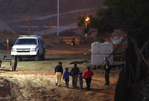(AP Photo/Rebecca Blackwell). Migrants traveling with children walk up a hill to a waiting U.S. Border Patrol agent just inside San Ysidro, Calif., after climbing over the border wall from Playas de Tijuana, Mexico, Monday, Dec. 3, 2018. Thousands of C... (AP Photo/Rebecca Blackwell). Migrants traveling with children walk up a hill to a waiting U.S. Border Patrol agent just inside San Ysidro, Calif., after climbing over the border wall from Playas de Tijuana, Mexico, Monday, Dec. 3, 2018. Thousands of C...