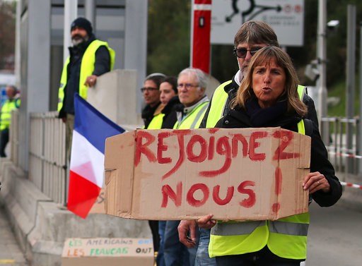 (AP Photo/Bob Edme). A demonstrator holds a placard reading " Join us" as they stand by toll gates on a motorway at Biarritz southwestern France, Wednesday, Dec.5, 2018. The concessions made by French president Emmanuel Macron's government in a bid to ... (AP Photo/Bob Edme). A demonstrator holds a placard reading " Join us" as they stand by toll gates on a motorway at Biarritz southwestern France, Wednesday, Dec.5, 2018. The concessions made by French president Emmanuel Macron's government in a bid to ...