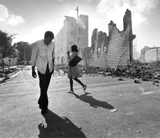 (AP Photo/Kathy Willens, File). FILE - In this May 19, 1980, photo, people walk past ruins in the Culmer section of Miami after rioting over the acquittal of four police officers charged with the 1979 beating death of Arthur McDuffie, a black motorcycl... (AP Photo/Kathy Willens, File). FILE - In this May 19, 1980, photo, people walk past ruins in the Culmer section of Miami after rioting over the acquittal of four police officers charged with the 1979 beating death of Arthur McDuffie, a black motorcycl...