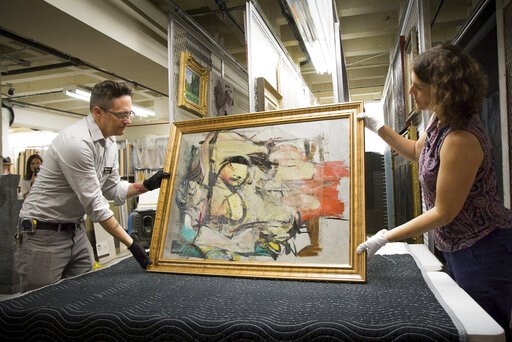 (Robert Demers/University of Arizona Communications via AP). This August 2017 photo shows "Woman-Ochre," a painting by Willem de Kooning, being readied for examination by University of Arizona Museum of Art staff Nathan Saxton, left, and Kristen Schmid...