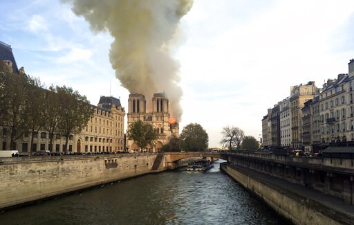 (AP Photo/Lori Hinant). Notre Dame cathedral is burning in Paris, Monday, April 15, 2019. Massive plumes of yellow brown smoke is filling the air above Notre Dame Cathedral and ash is falling on tourists and others around the island that marks the cent... (AP Photo/Lori Hinant). Notre Dame cathedral is burning in Paris, Monday, April 15, 2019. Massive plumes of yellow brown smoke is filling the air above Notre Dame Cathedral and ash is falling on tourists and others around the island that marks the cent...