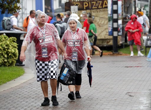 (AP Photo/John Raoux). Fans walk through the Fan Zone during a weather delay of activities before the NASCAR Cup Series auto race at Daytona International Speedway, Saturday, July 6, 2019, in Daytona Beach, Fla.