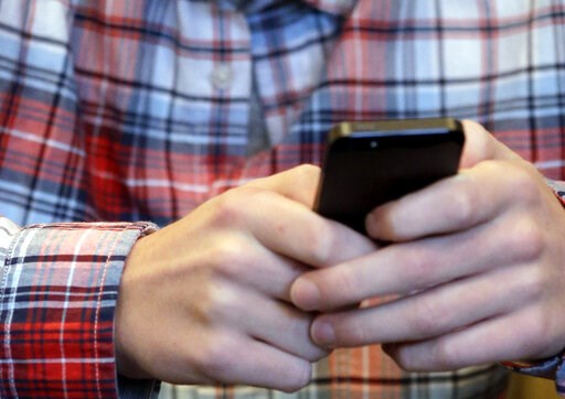 (AP Photo/Nam Y. Huh, File). FILE - In this Oct. 24, 2013, file photo, a person checks their smartphone in Glenview, Ill. A mysterious wave of texts swept America’s phones overnight Wednesday, Nov. 6, 2019, delivering unintelligible messages that left ...